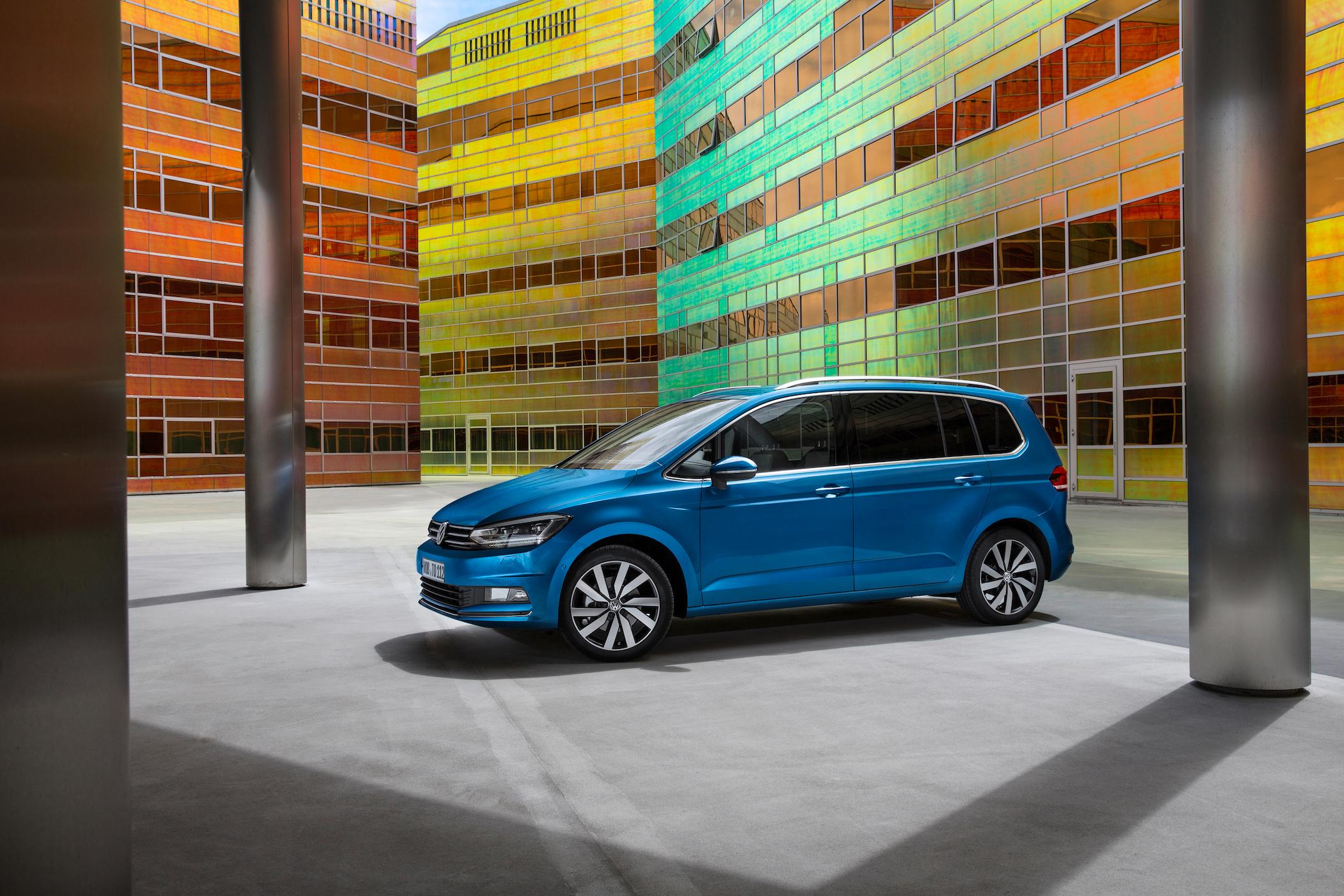 blue volkswagen touran parked among brightly-coloured buildings